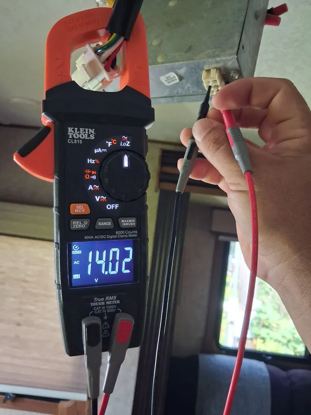 Hands using a meter to test an RV air-conditioning system